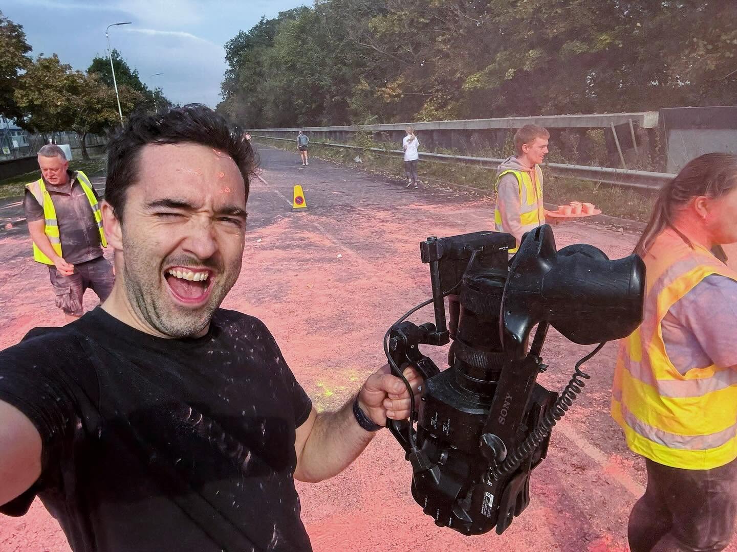 A member of the SlackPress crew with a camera rig at an outdoor colour run.