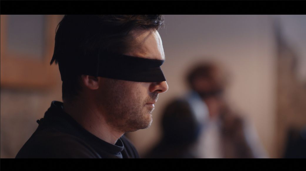 A close-up of a blindfolded male performer in the Speak Up campaign film.